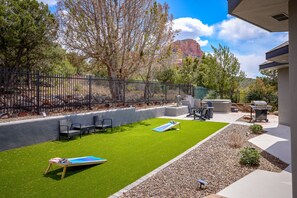 A backyard with artificial grass, outdoor furniture, and a barbecue area.