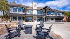 A modern two-story house with a large driveway, outdoor seating area, and a garage.