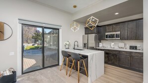 A modern kitchen with a large island, dark cabinets, and a sliding glass door leading to a patio.