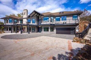 A modern two-story house with a large driveway, a stone staircase, and a garage.