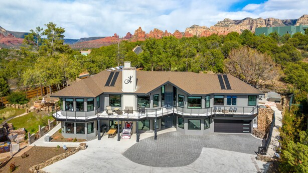 A modern house with a large patio, multiple decks, and a view of red rock formations.