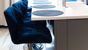 A modern kitchen with a central island, a blue chair, and a pendant light. - Notre Dame Home Steps to Campus w/ Hot Tub (South Bend)