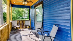 A covered porch with wooden flooring, a ceiling fan, and two chairs. - Notre Dame Home Steps to Campus w/ Hot Tub (South Bend)