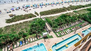 A resort with a pool area, beach, and lounge chairs.