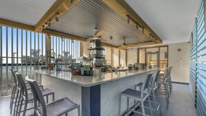 A bar area with a marble countertop, bar stools, and a view of the ocean.