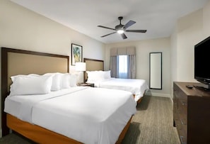 Two single beds with white linens, a ceiling fan, flat-screen TV, and large mirror.