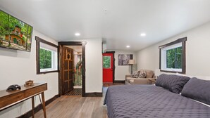 Un dormitorio con una cama grande, un escritorio, una silla y una puerta que da a otra habitación.