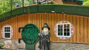 Un edificio de madera con una puerta verde, una estatua de un mago y una ventana de mosaico.