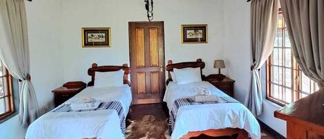 A room with two wooden beds, a ceiling fan, and a wooden door.