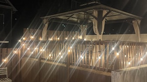 Um deck de madeira com área de estar coberta e luzes de corda.