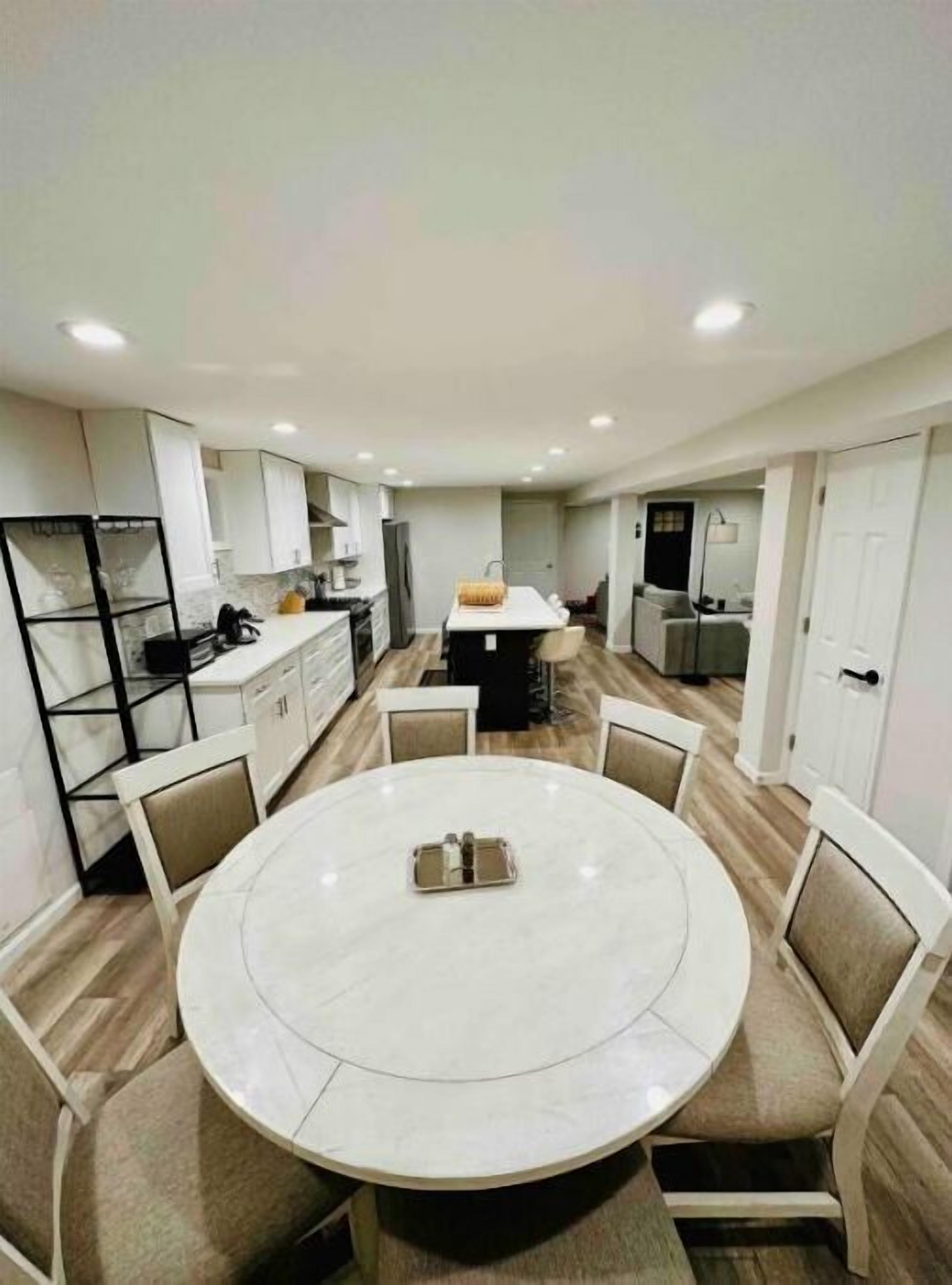 Een moderne keuken met witte kasten, een centraal eiland en een eethoek met een ronde tafel en stoelen.