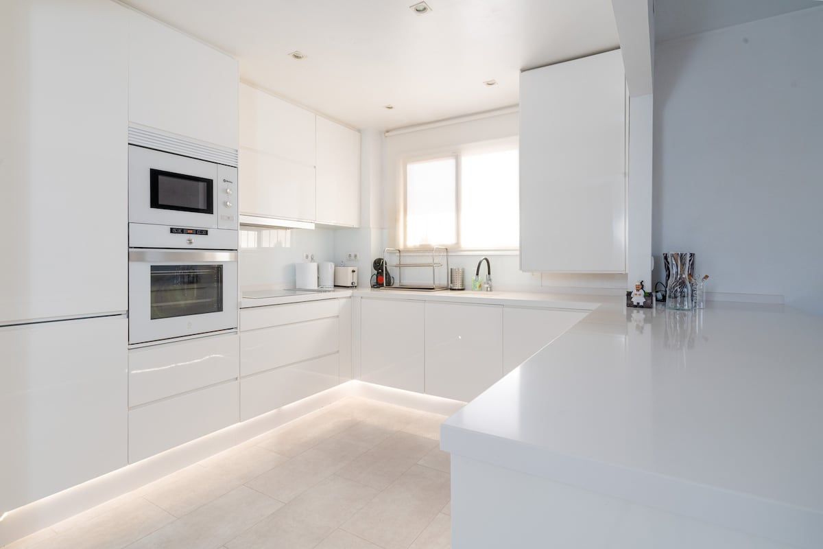 A modern kitchen with white cabinetry, a built-in oven, and a microwave.