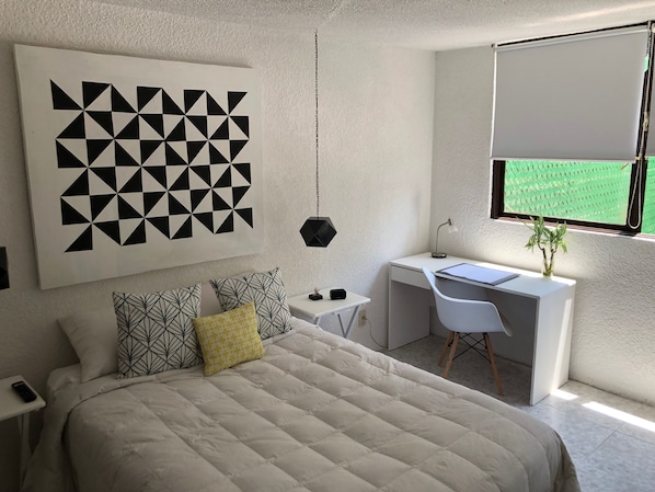 Une chambre moderne avec un grand lit, un bureau et une fenêtre donnant sur un paysage verdoyant.