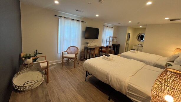 A hotel room with two beds, a desk, a chair, a TV, and a mirror.