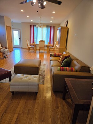 A spacious living area with a sofa, ottoman, and a dining table with chairs. - Unique and Chic home. rooftop deck, near lakefront. Easy commute to downtown. (Chicago)