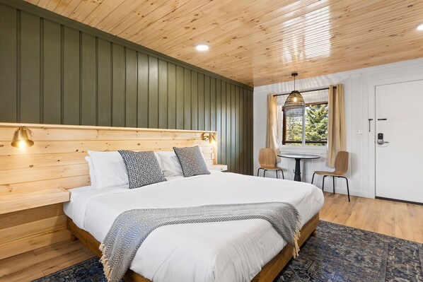 Cozy retreat with a large bed, wooden headboard, and a small table for two.