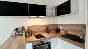 A modern kitchen with white cabinets, a wooden countertop, a built-in oven, a sink, and a microwave. - La Voile Grise des Dunes (Koksijde)
