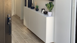 A modern hallway with a white reception desk, a mounted flat-screen TV, and a painting on the wall. - La Voile Grise des Dunes (Koksijde)
