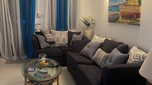 A living room with a sectional sofa, a glass coffee table, and a ceiling fan.