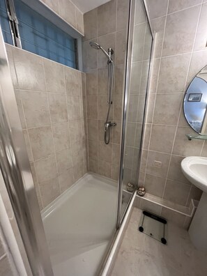 Une salle de bain avec une douche à parois de verre, un lavabo blanc et un miroir au mur.