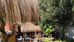 A thatched-roof structure, a wooden hand sculpture, and a rope barrier in a garden setting. - Parcela Los Nonos (Vicuña)
