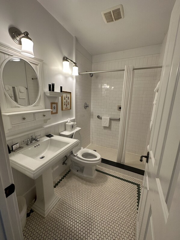 A bathroom with a white sink, toilet, and shower area. - Buttermilk Falls Inn (Milton)