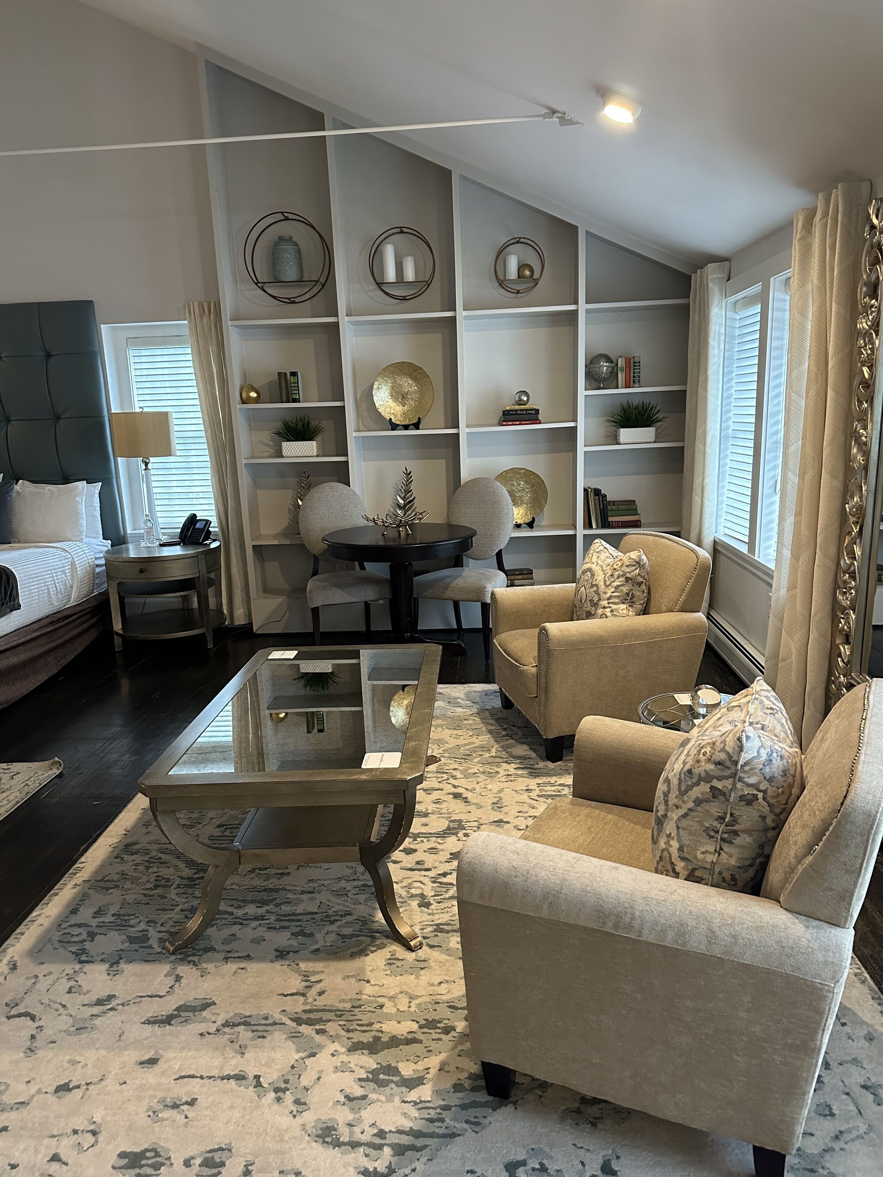Ein Wohnzimmer mit Sofa, Sesseln, Couchtisch und Bücherregal.