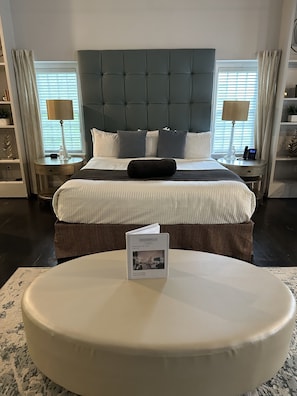 A hotel room with a large bed, a bedside table with a lamp, and a bedside shelf.
