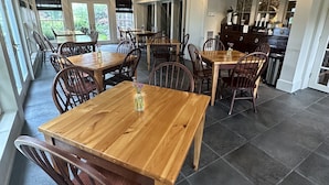 A spacious dining area with wooden tables and chairs, large windows, and ceiling fans. - Buttermilk Falls Inn (Milton)