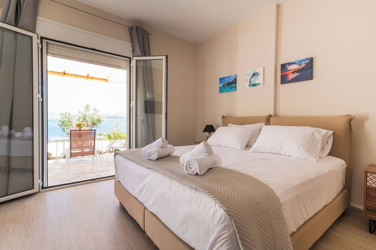 A bedroom with a bed, a sliding glass door to a balcony, and two wall-mounted pictures.