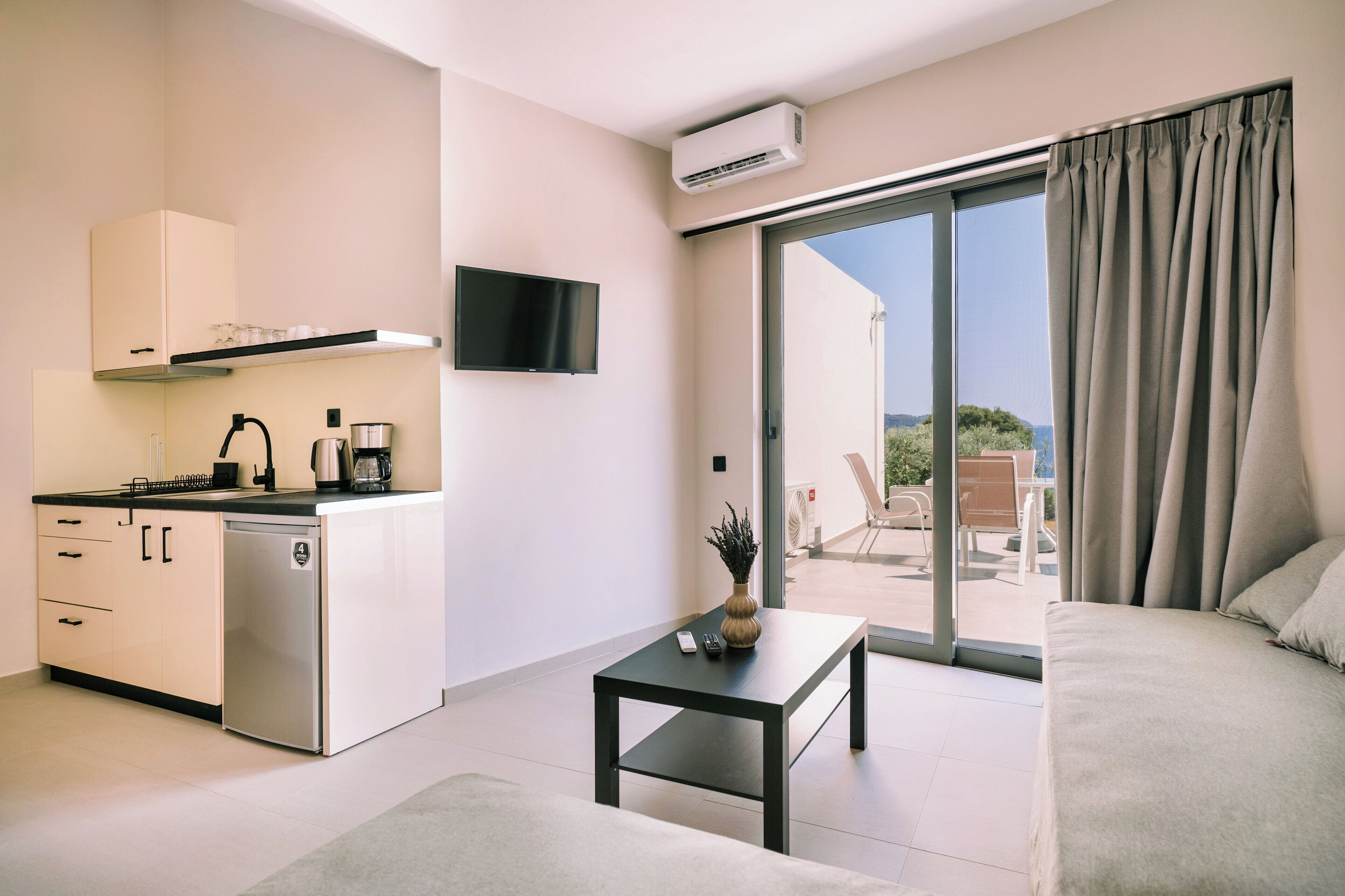 A modern kitchen with a built-in dishwasher, a flat-screen TV, and a dining area with a table and chairs.