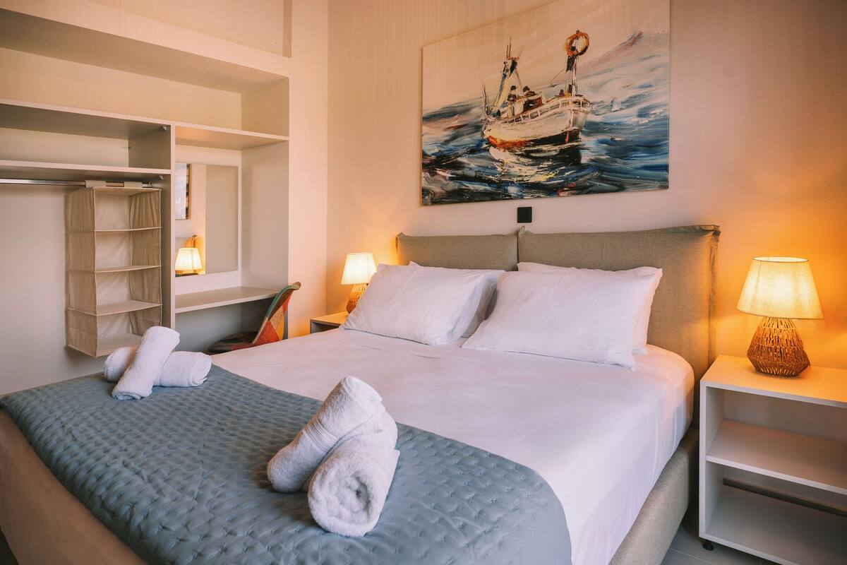 A neatly made bed with white linens, a headboard, and two bedside lamps.