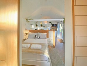 Une chambre moderne avec un grand lit, des lampes de chevet et une vue sur la cuisine.