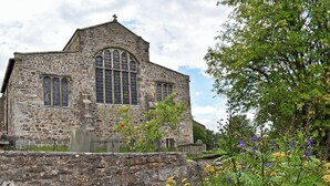 Une église en pierre dotée d’une grande fenêtre en arc de cercle et d’un clocher.