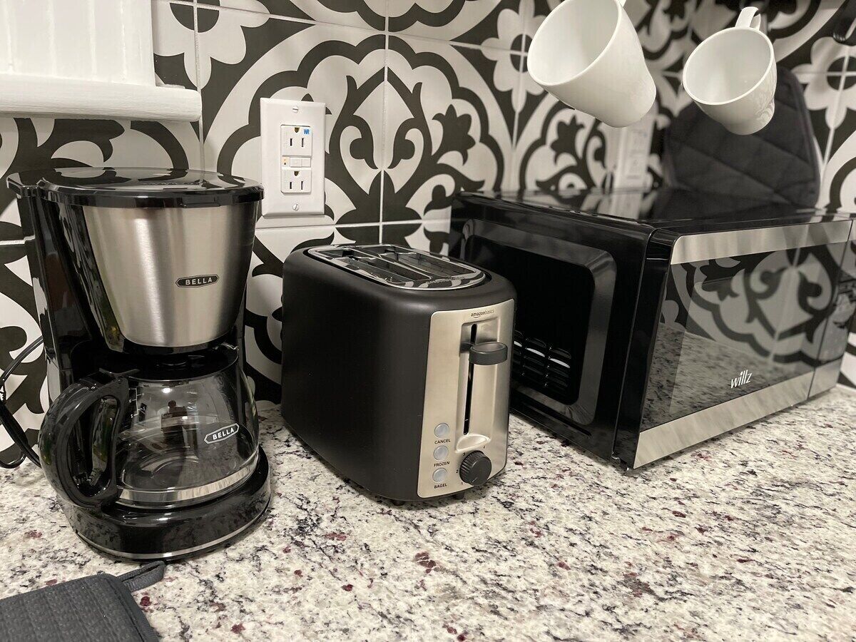A kitchen with a coffee maker, toaster, and microwave.