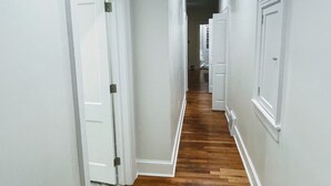 Un couloir aux murs blancs et au plancher en bois.