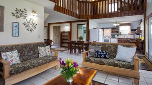 A spacious living area with two sofas, a coffee table, and a decorative plant. A wooden staircase leads to an upper level. - Heron Hill at Secluded Cabins (Lakeville)