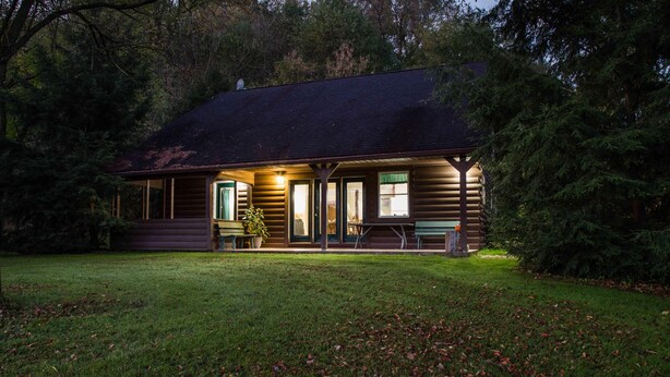 A log cabin with a porch, a bench, and a table. - Heron Hill at Secluded Cabins (Lakeville)