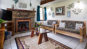 A living room with a stone fireplace, wooden furniture, and decorative wall art. - Heron Hill at Secluded Cabins (Lakeville)
