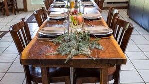 A long wooden dining table set for six with chairs, a decorative centerpiece, and a view of the outdoors through a glass door. - Heron Hill at Secluded Cabins (Lakeville)