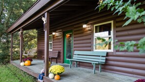 A wooden cabin with a porch, a bench, and potted plants. - Dove Cottage at Secluded Cabins (Lakeville)