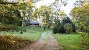 A rustic cabin with a gravel path leading to it, surrounded by lush greenery and trees. - Dove Cottage at Secluded Cabins (Lakeville)