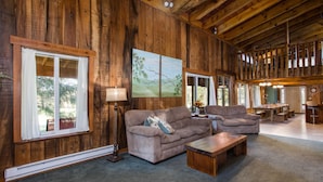 A spacious living room with wooden walls, a large window, and a fireplace.