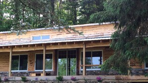 A log cabin with a stone foundation, large windows, and a stone retaining wall.
