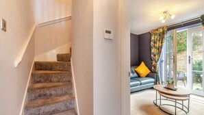 Una escalera conduce a una sala de estar con un sofá, una mesa de centro y vistas a través de un ventanal.
