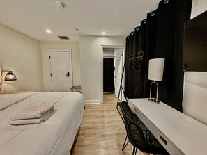 A hotel room with a bed, a desk, a chair, a lamp, and a curtain. - 6BR Crew Stay - Kitchen - Parking - Near I-26 - C (North Charleston)