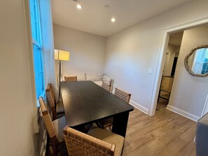 A dining area with a dark wooden table, wicker chairs, and a light-colored sofa. - 6BR Crew Stay - Kitchen - Parking - Near I-26 - C (North Charleston)