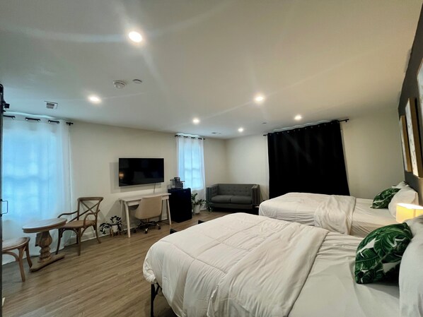 Une chambre d’hôtel avec deux lits, un bureau, une chaise, une télévision et une fenêtre avec des rideaux.