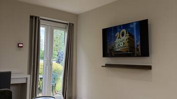En moderne stue med sofa, et lille rundt bord og et fladskærms-tv monteret på væggen.