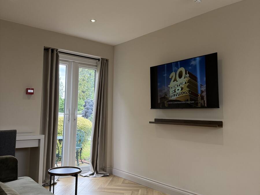 En moderne stue med sofa, et lille rundt bord og et fladskærms-tv monteret på væggen.